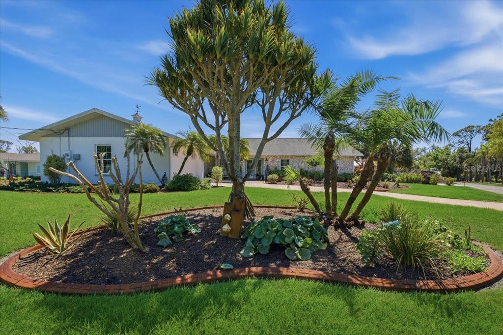 A house exterior features a brick paver driveway, a two-car garage, and stone wall accents — 1231 BAYSHORE DRIVE, ENGLEWOOD, FL