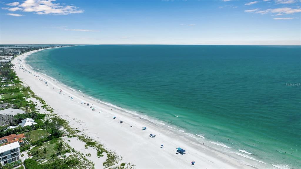 An aerial view shows a white sand beach along a turquoise ocean under a blue sky — 210 84TH STREET, BRADENTON BEACH, FL
