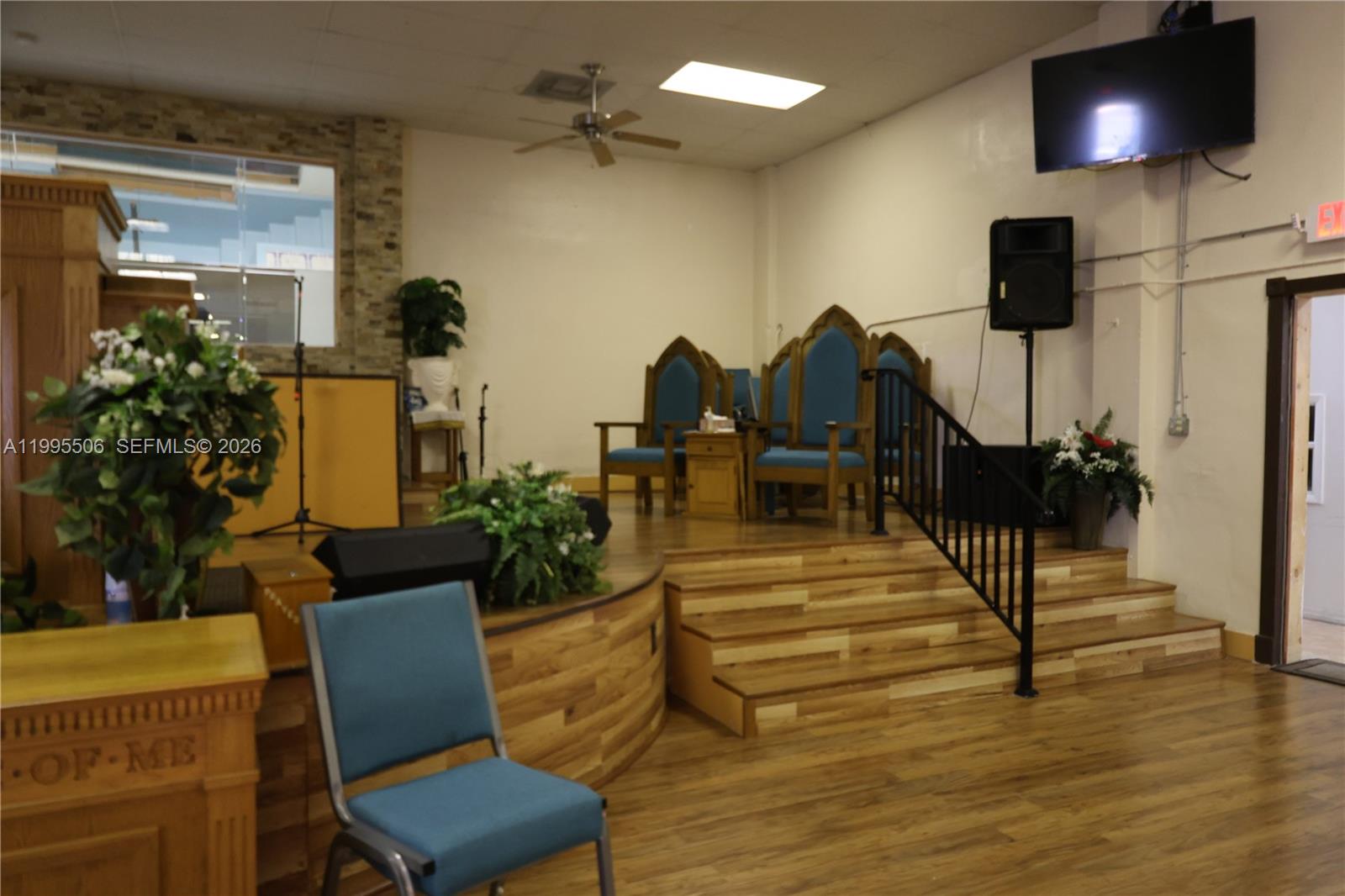 A church sanctuary features a wooden stage with blue chairs, a podium, and speakers — 4343 NW 17th Ave, Miami FL 33142, MIAMI, FL
