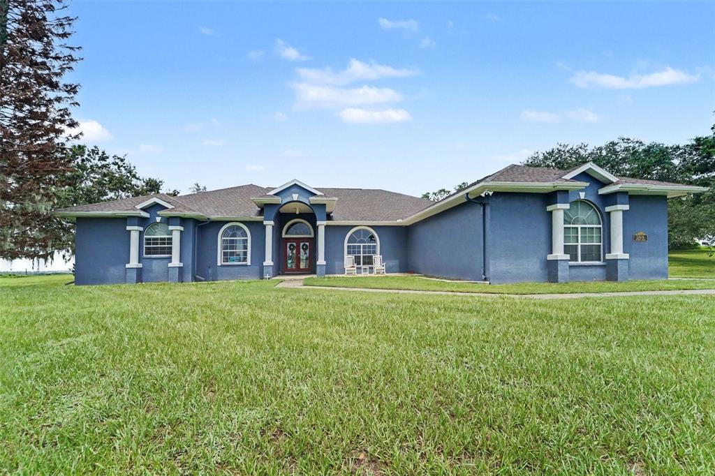 A blue, single-story house with a prominent arched entryway and a large front lawn — 37616 SKY RIDGE CIRCLE, DADE CITY, FL