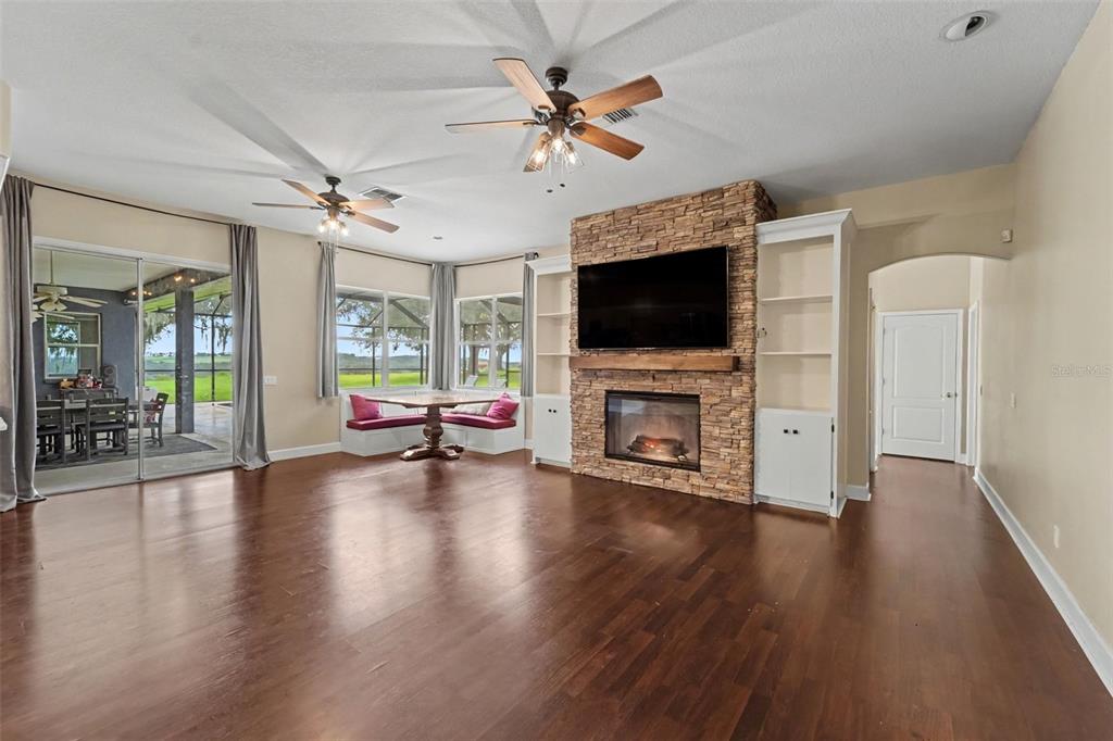 A living room features hardwood floors, a stone fireplace with built-in shelves, and a dining nook — 37616 SKY RIDGE CIRCLE, DADE CITY, FL