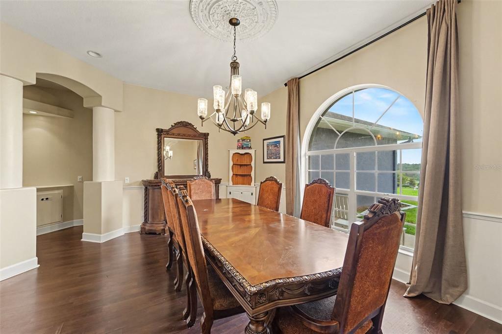 A formal dining room features a wooden table, six chairs, a chandelier, and arched windows — 37616 SKY RIDGE CIRCLE, DADE CITY, FL
