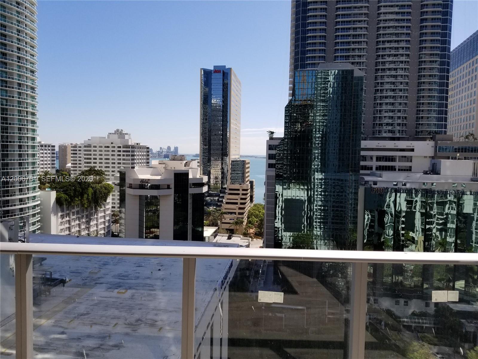 A balcony view overlooks a dense urban skyline with several high-rise buildings and water — 1010 Brickell Ave # 3205, Miami FL 33131, MIAMI, FL