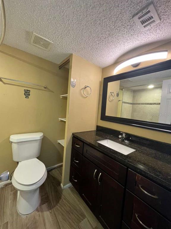 A bathroom features a toilet, a dark wood vanity with a granite countertop, and a mirror — 131 WATER FRONT WAY UNIT 220, ALTAMONTE SPRINGS, FL