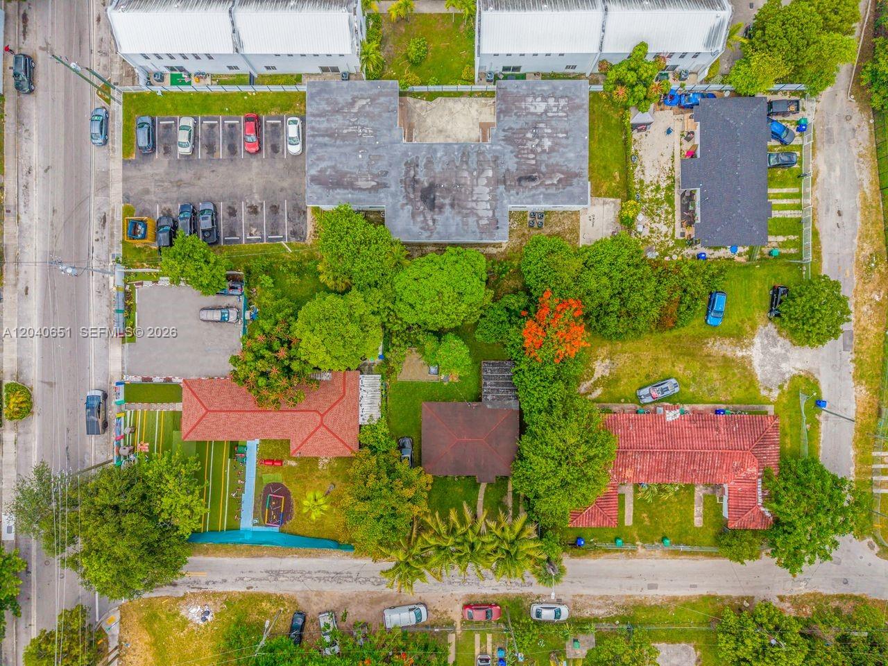 An aerial view shows several residential buildings with red-tiled roofs, parking lots, and green landscaping — 7722 NW 1st Ave, Miami FL 33150, MIAMI, FL