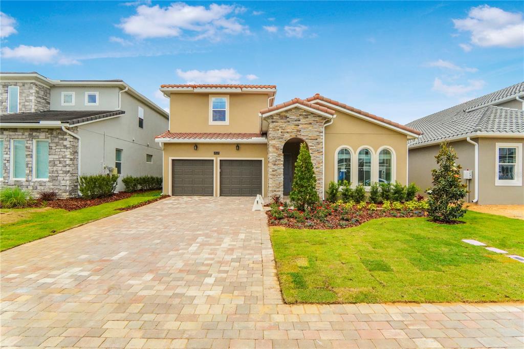 A two-story house with a stone facade, arched windows, and a paved driveway — 16120 VOLTERRA POINT, MONTVERDE, FL