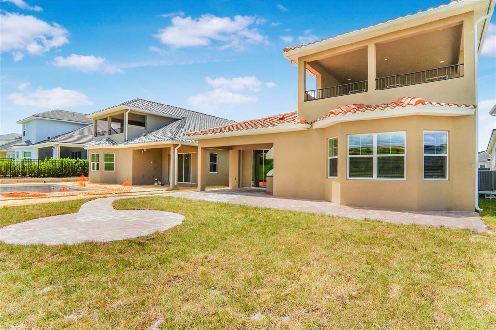 The rear exterior of a two-story tan stucco house with a covered patio and balcony — 16120 VOLTERRA POINT, MONTVERDE, FL
