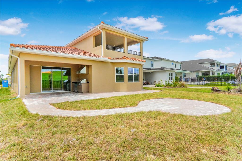The exterior view shows a tan stucco house with a covered patio, outdoor kitchen, and pavers — 16120 VOLTERRA POINT, MONTVERDE, FL