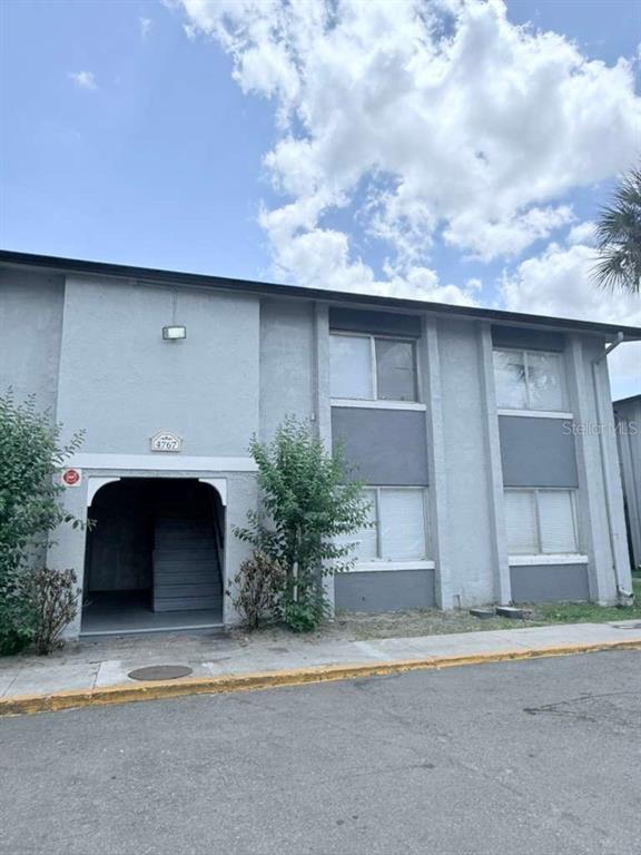A two-story apartment building exterior features gray stucco walls and a covered stairwell entrance — 4767 S TEXAS AVENUE UNIT 4767B, ORLANDO, FL