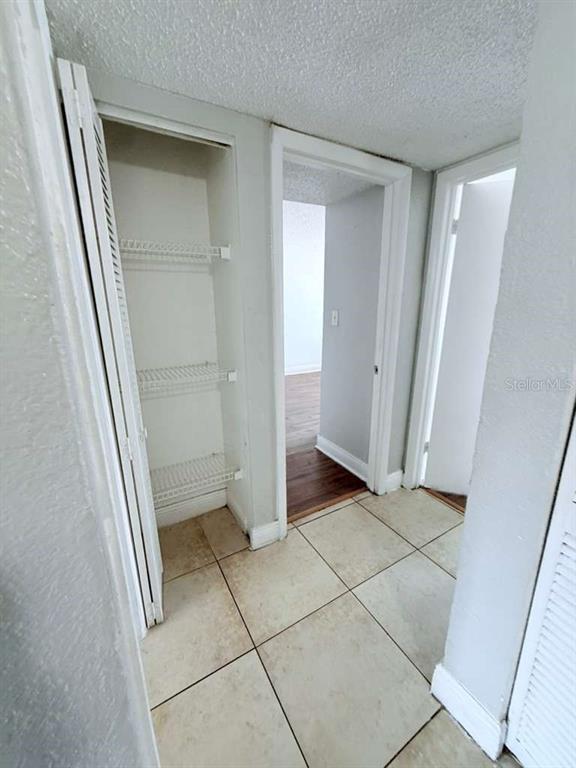A hallway with tiled floors features an open linen closet and two doorways — 4767 S TEXAS AVENUE UNIT 4767B, ORLANDO, FL