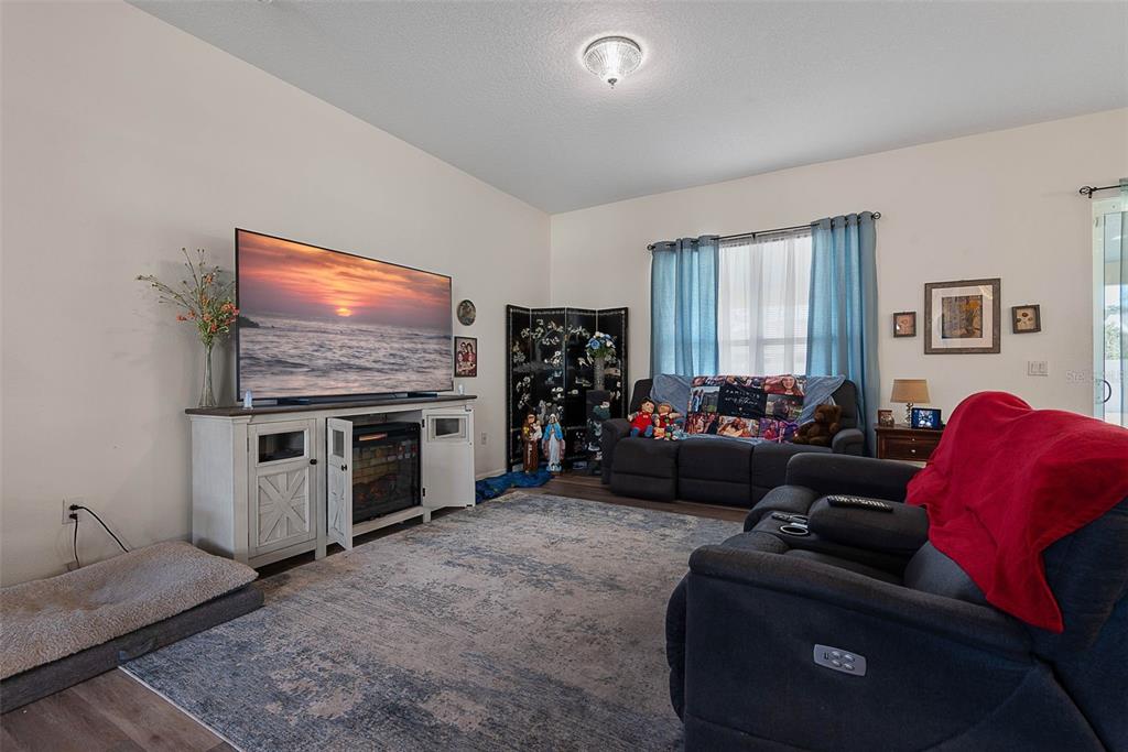 A living room features a large television on a white console, gray recliners, and a rug — 16 WHITE HAVEN LANE, PALM COAST, FL