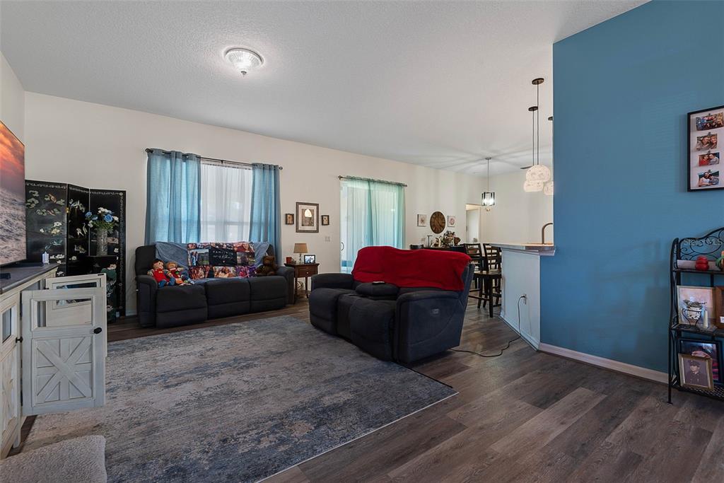 A living room features dark gray sofas, a blue accent wall, and wood-look flooring — 16 WHITE HAVEN LANE, PALM COAST, FL