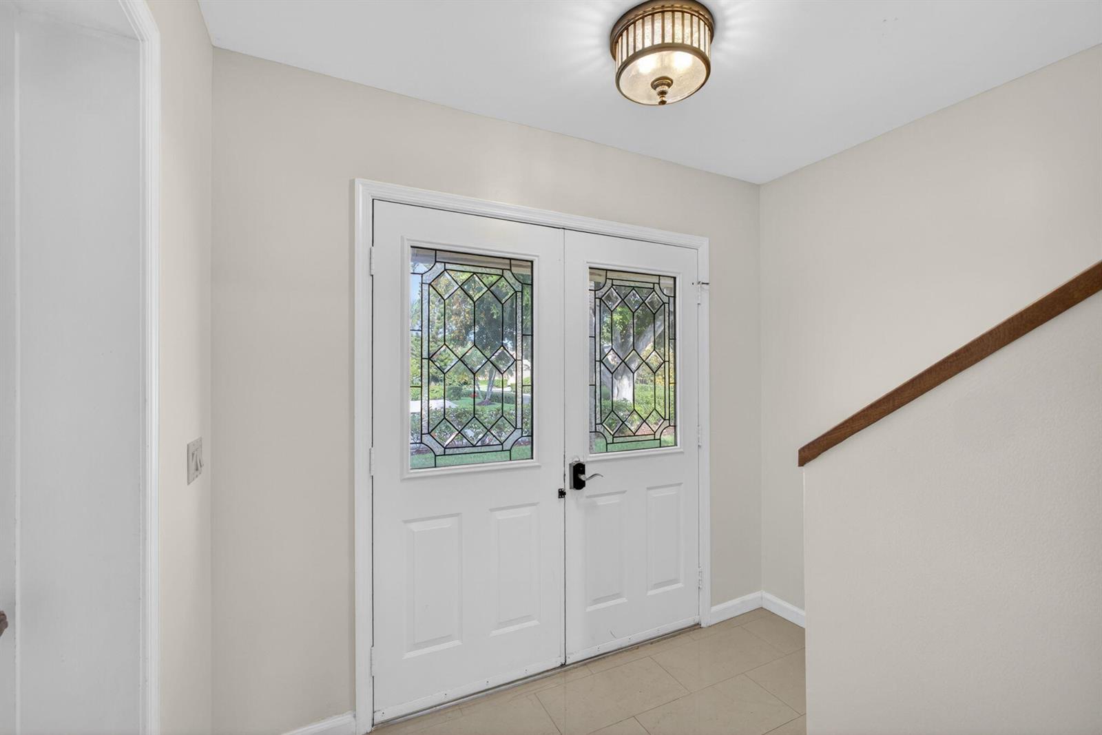 A foyer features a double front door with decorative glass panels and a ceiling light — 17137 Waterbend Drive # 204, Jupiter FL 33477, JUPITER, FL