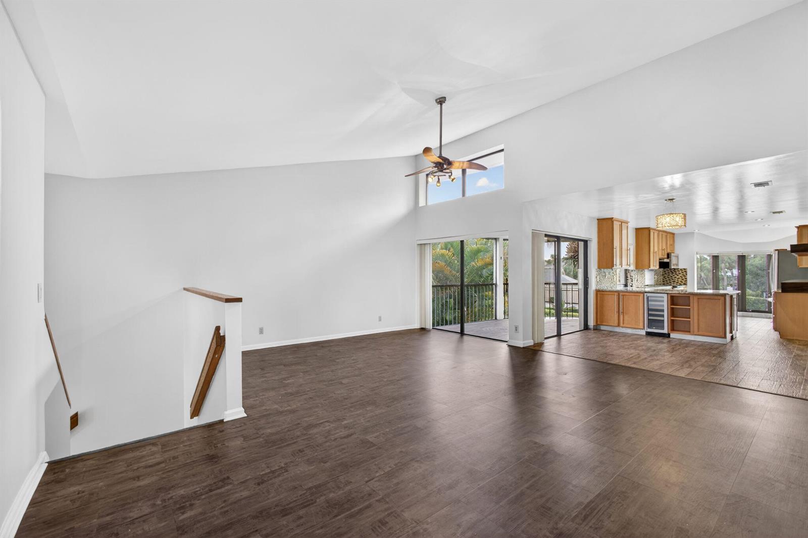 An open-concept living area with vaulted ceilings, dark wood-look flooring, and an adjacent kitchen — 17137 Waterbend Drive # 204, Jupiter FL 33477, JUPITER, FL