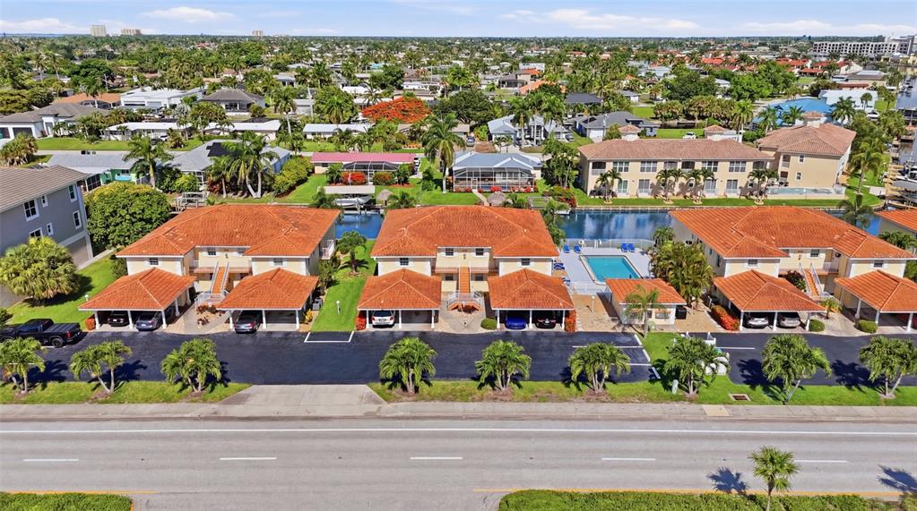 An aerial view shows three multi-unit residential buildings with orange roofs and covered parking — 5112 CORONADO PARKWAY UNIT 12, CAPE CORAL, FL