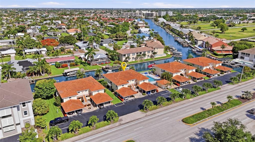 An aerial view shows multi-unit residential buildings with tile roofs and carports along a canal — 5112 CORONADO PARKWAY UNIT 12, CAPE CORAL, FL