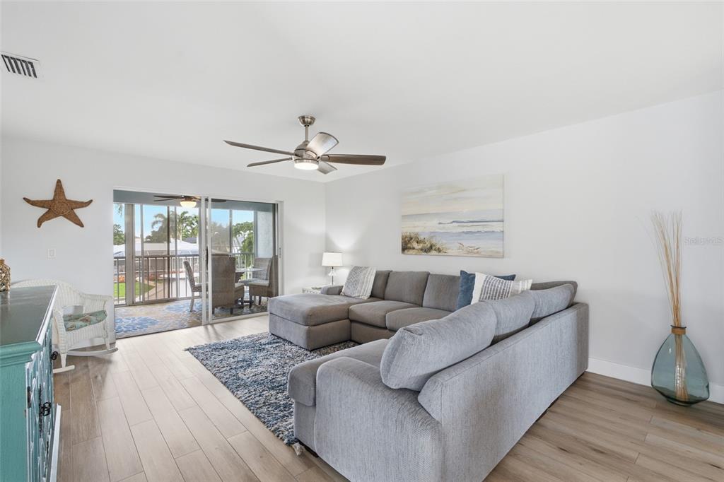 A living room features a grey sectional sofa, a blue area rug, and sliding glass doors — 5112 CORONADO PARKWAY UNIT 12, CAPE CORAL, FL