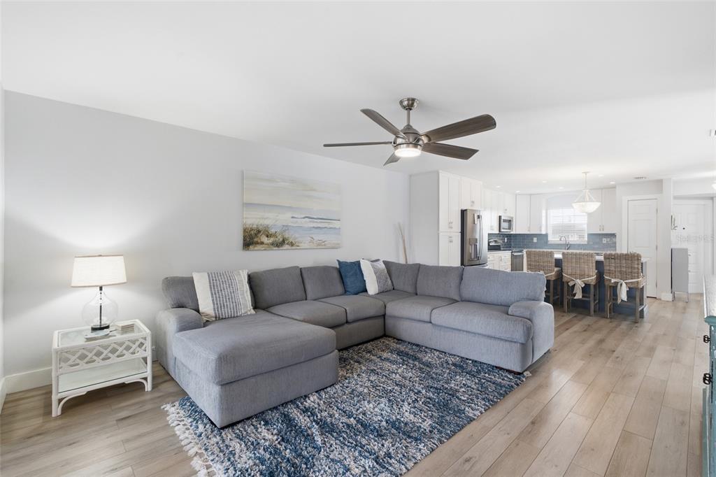 A living room with a gray sectional sofa, blue area rug, and an open kitchen — 5112 CORONADO PARKWAY UNIT 12, CAPE CORAL, FL