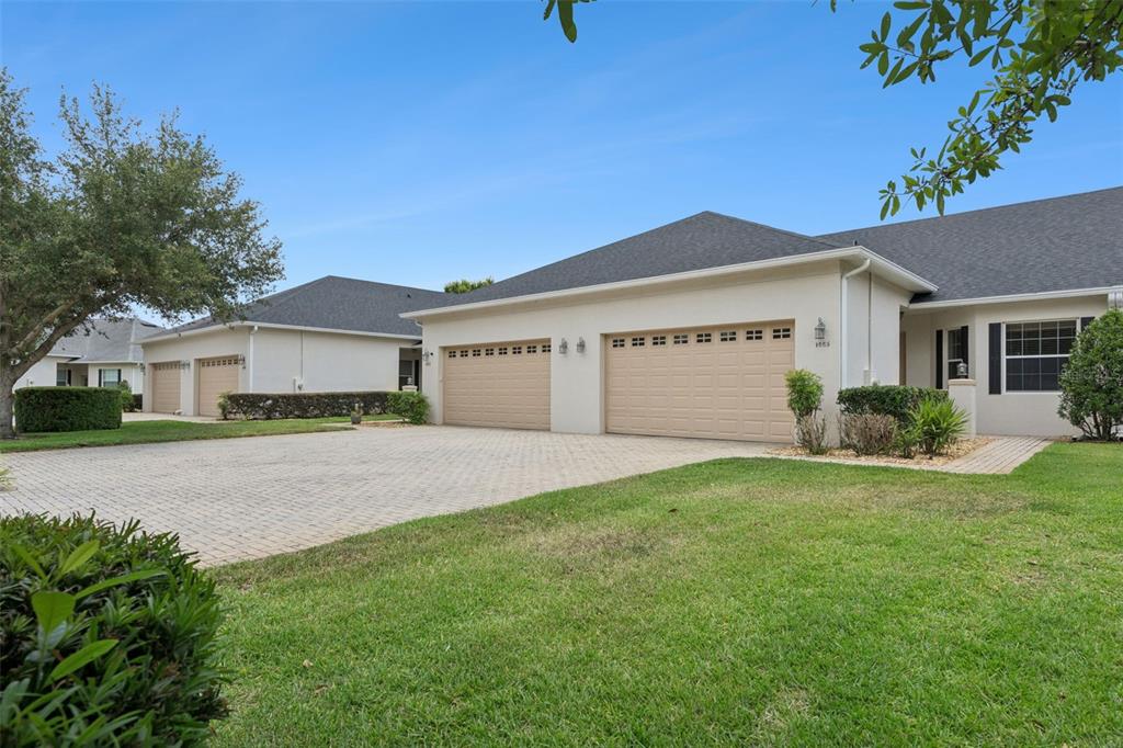 A beige house with a three-car garage and a paved driveway under a blue sky — 1005 GREEN GATE BOULEVARD, GROVELAND, FL