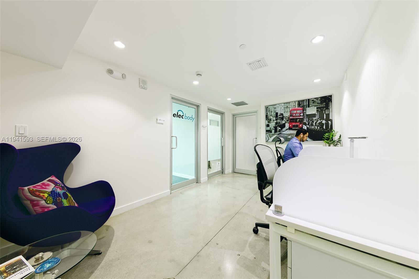 A modern office space features a purple egg chair, white desks, and concrete flooring — 350 S Miami Ave, Miami FL 33130, MIAMI, FL