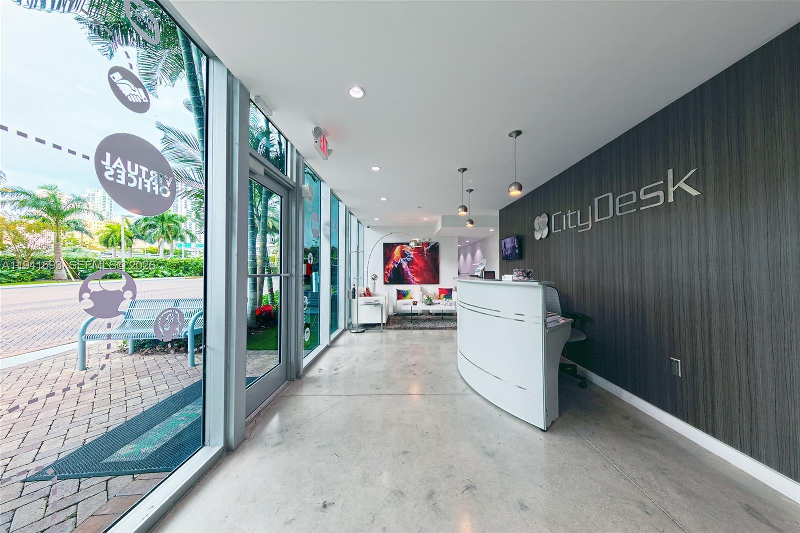 A modern office reception area features a curved white desk, wood-paneled wall, and glass doors — 350 S Miami Ave, Miami FL 33130, MIAMI, FL