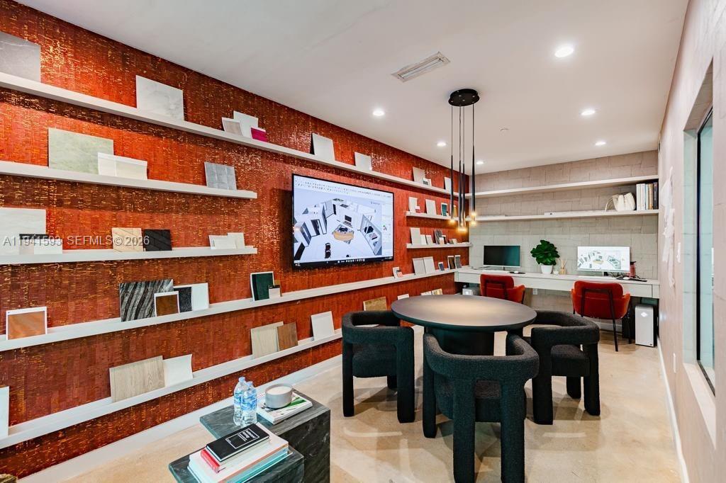 A modern office features a red textured wall with shelving, a round table, and desks — 350 S Miami Ave, Miami FL 33130, MIAMI, FL