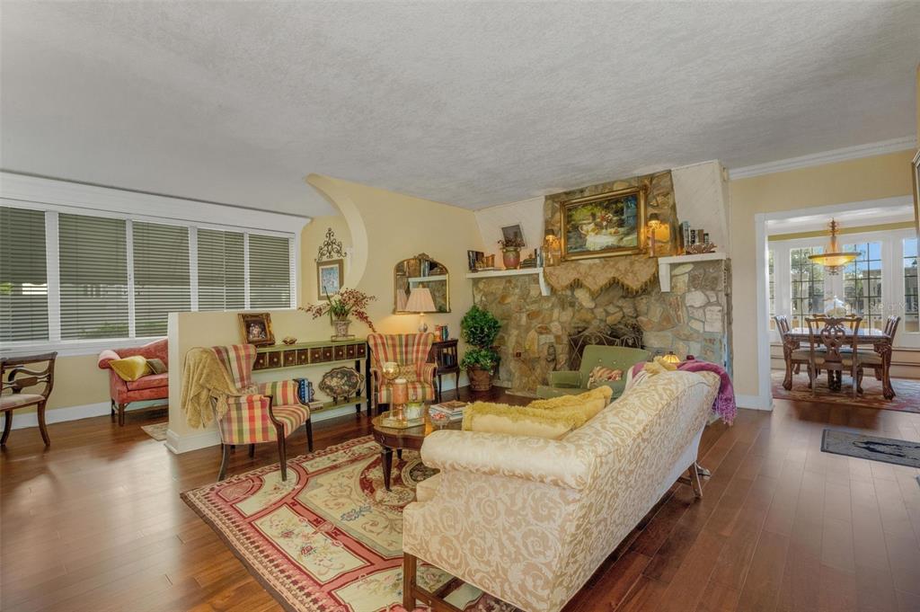 A living room with hardwood floors, a stone fireplace, and a dining area beyond — 2015 E BEACON BY WAY, LAKELAND, FL