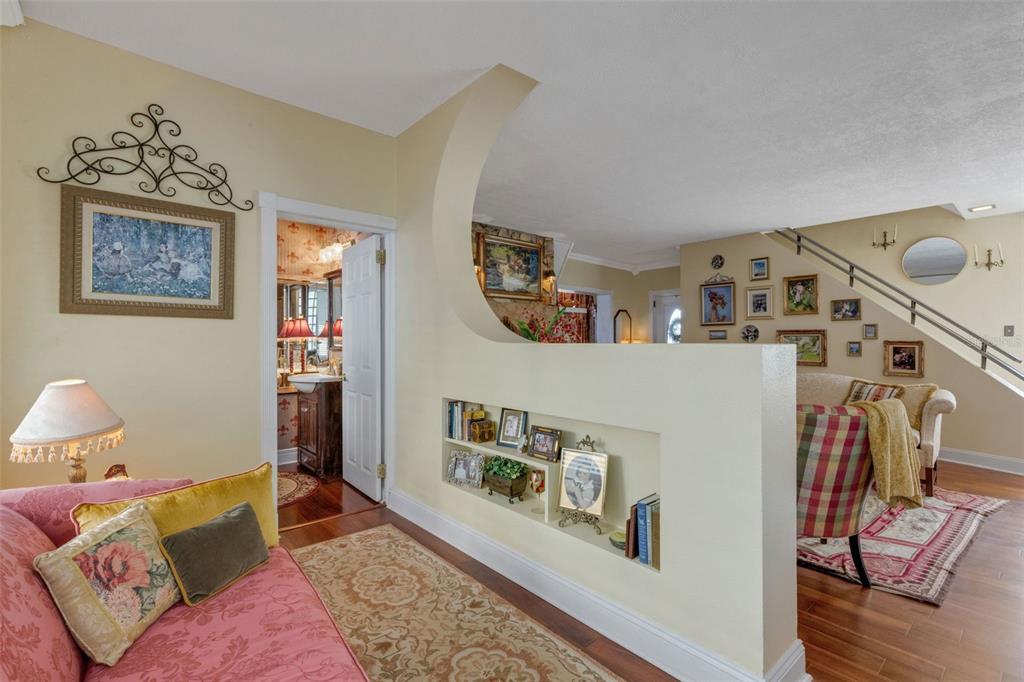 A living room features a half-wall with built-in shelving, hardwood floors, and a staircase — 2015 E BEACON BY WAY, LAKELAND, FL