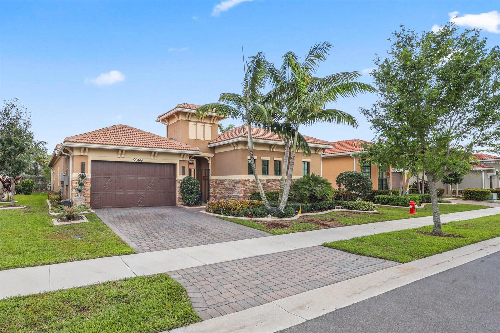 A single-story house with a brown garage, tile roof, and a palm tree in front — 9368 Cantal Circle E, Parkland FL 33076, PARKLAND, FL