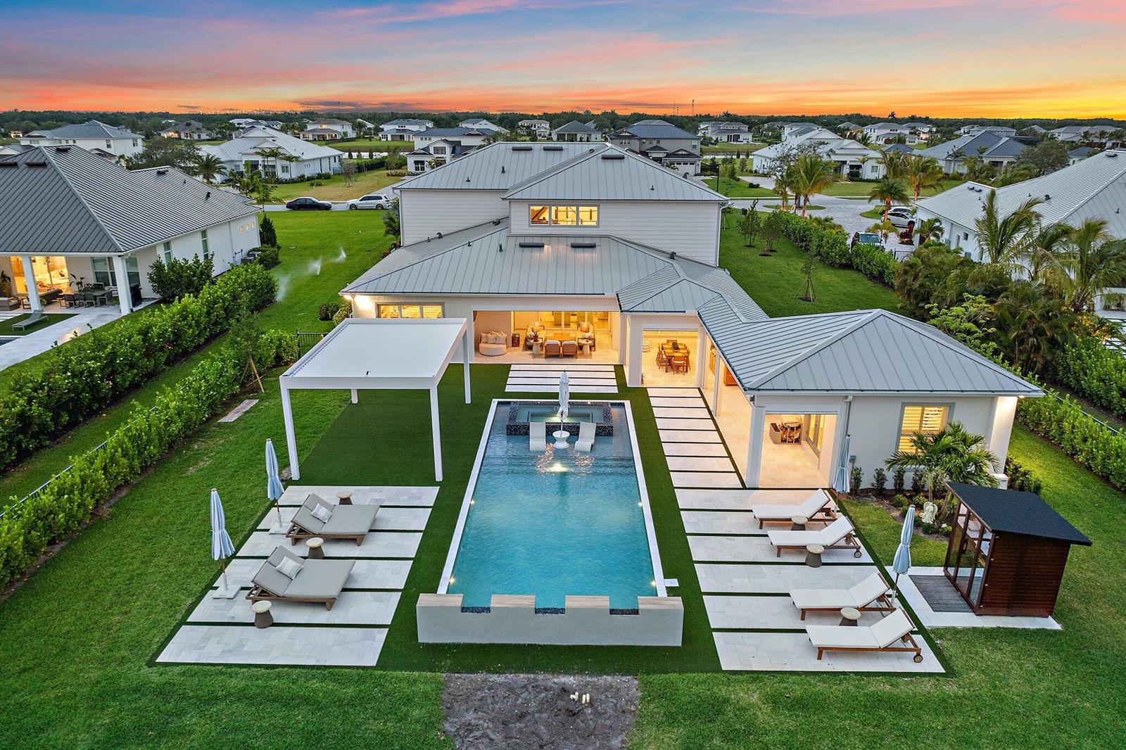 An aerial view of a house with a swimming pool, patio, and landscaped backyard at sunset — 20065 SE Bridgewater Drive, Jupiter FL 33458, JUPITER, FL