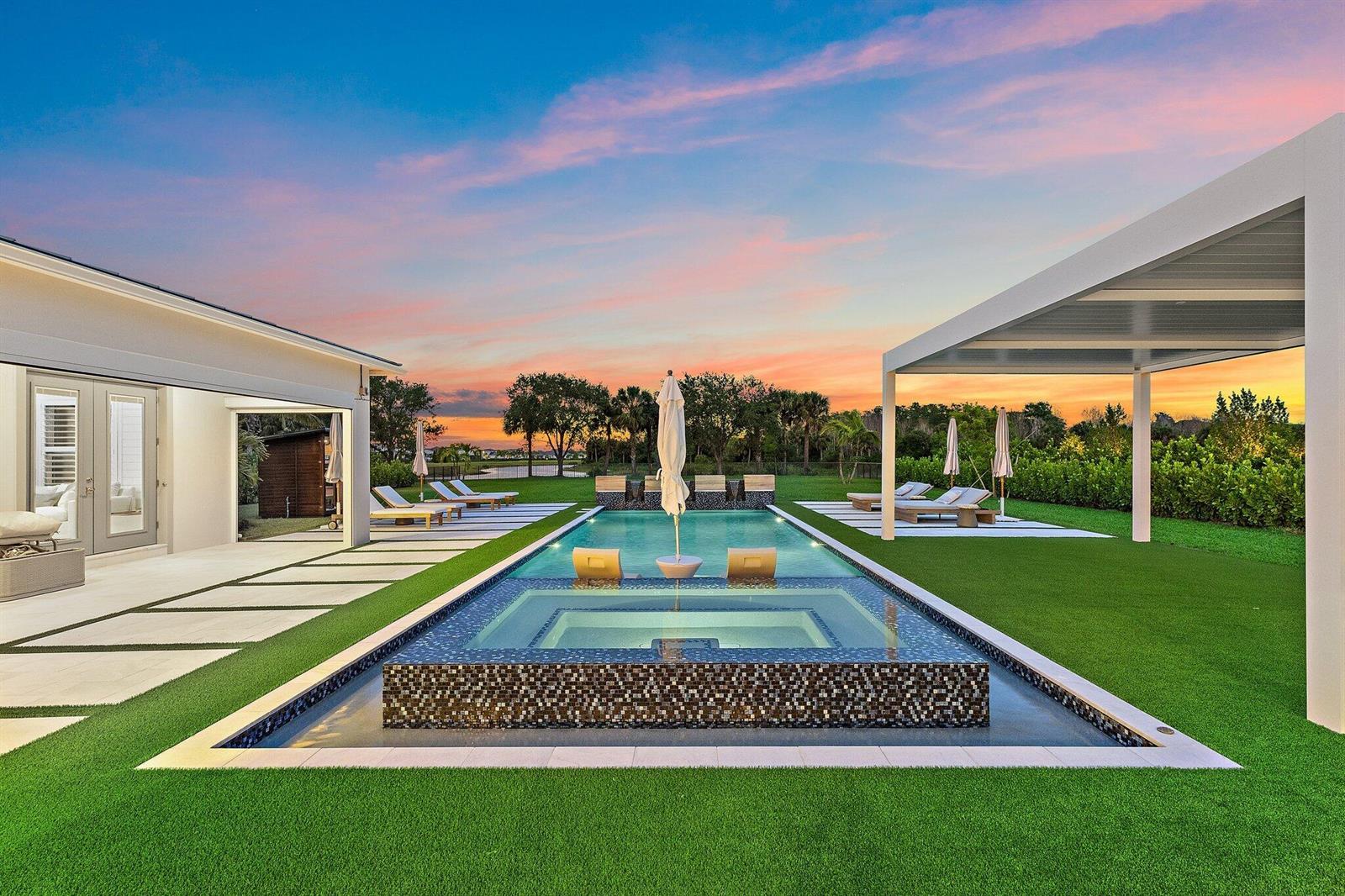 A backyard features a rectangular swimming pool with an integrated hot tub and lounge chairs — 20065 SE Bridgewater Drive, Jupiter FL 33458, JUPITER, FL