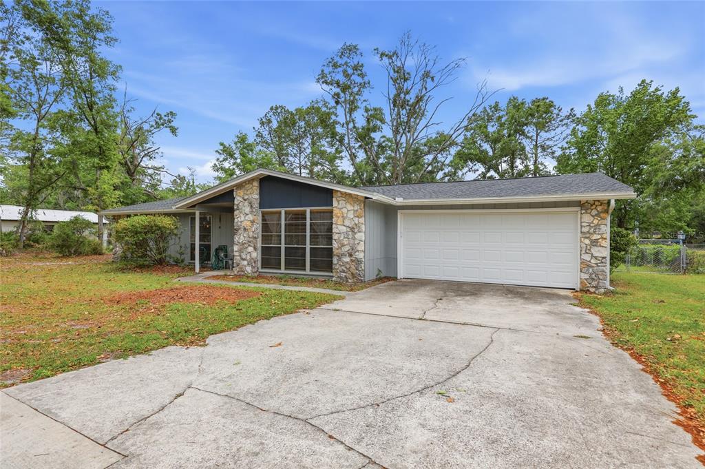 A single-story house with a stone facade, gray siding, and a two-car garage — 2921 NW 54TH AVENUE, GAINESVILLE, FL