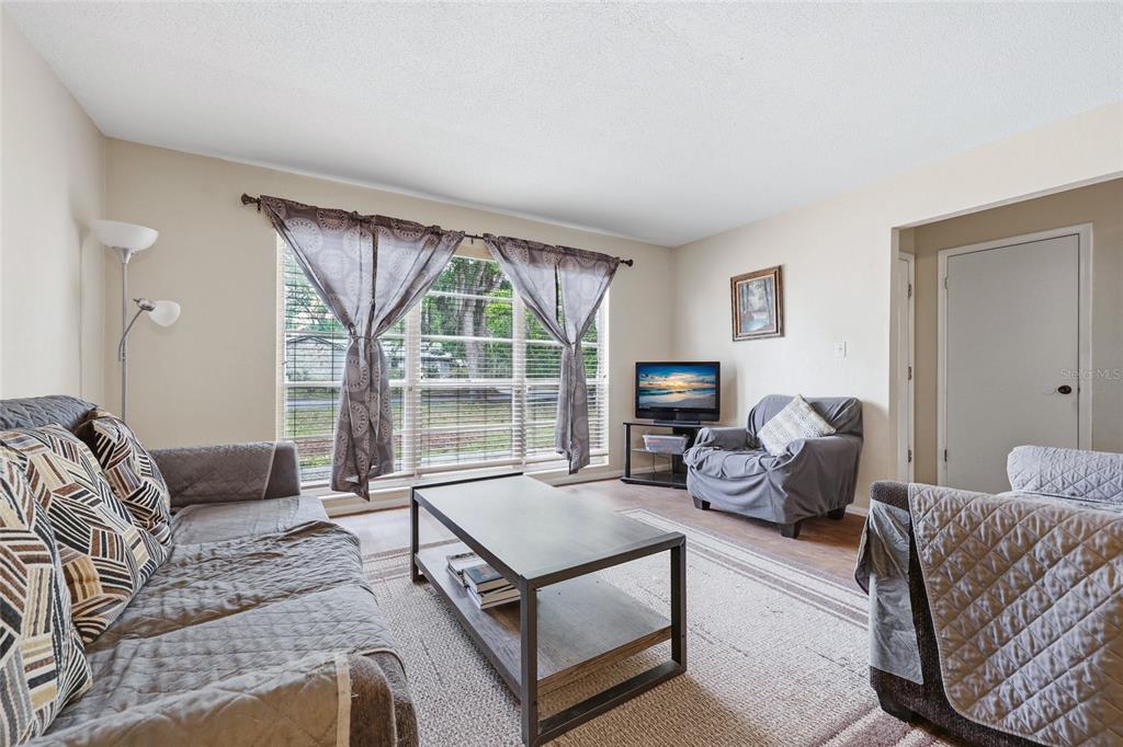 A living room features a sofa, an armchair, a coffee table, and a large window — 2921 NW 54TH AVENUE, GAINESVILLE, FL