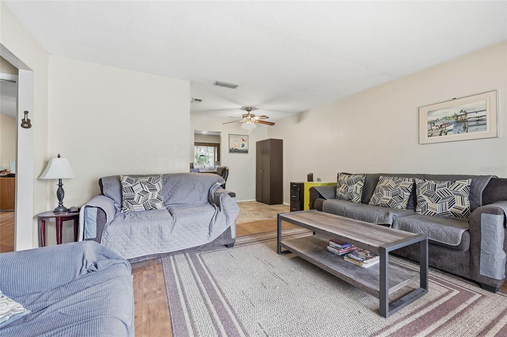 A living room features two gray sofas, a wooden coffee table, and a striped rug — 2921 NW 54TH AVENUE, GAINESVILLE, FL