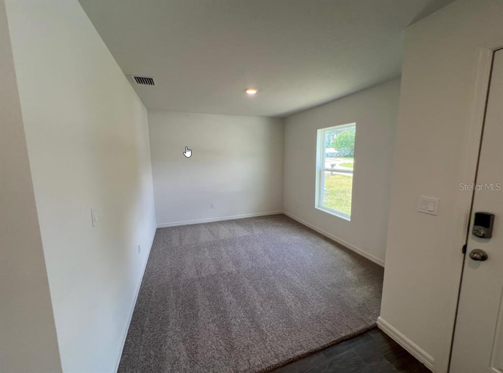 An empty room with gray carpet, white walls, and a single window — 76 RALEIGH DRIVE, PALM COAST, FL
