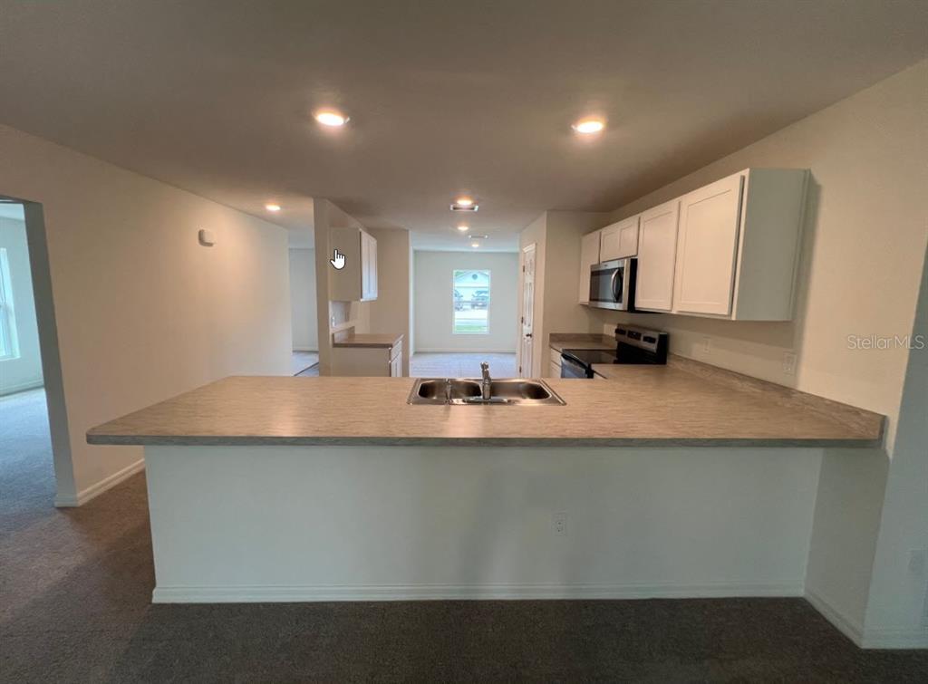A kitchen features a breakfast bar, laminate countertops, and white cabinets — 76 RALEIGH DRIVE, PALM COAST, FL