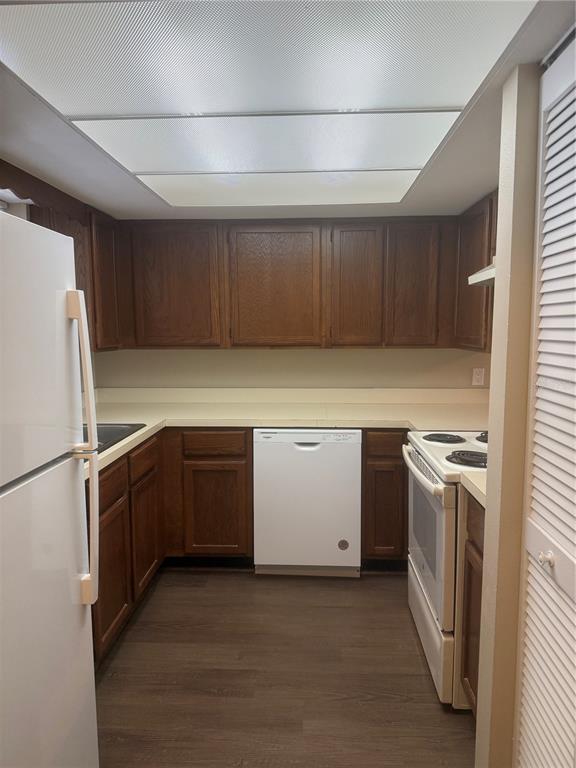 A galley kitchen features wood cabinets, white appliances, and light-colored countertops — 607 COUNTRY LANE NE UNIT 607, WINTER HAVEN, FL