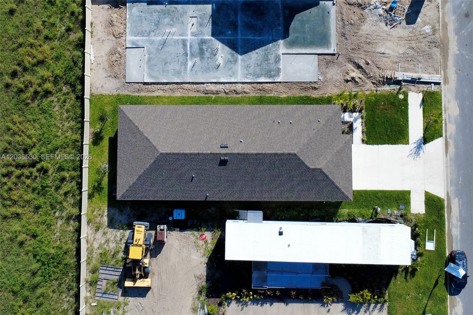 An aerial view shows a house with a dark roof next to a construction site — 5539 MADDIE DR, Davenport FL 33844, DAVENPORT, FL