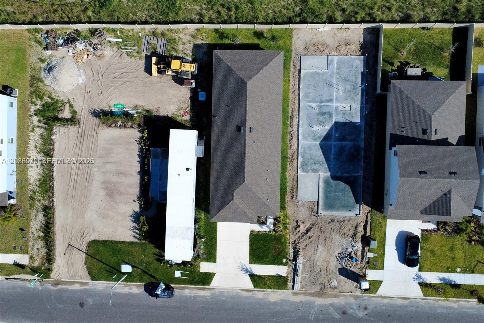 An aerial view shows a residential street with a completed house, a concrete foundation, and construction sites — 5539 MADDIE DR, Davenport FL 33844, DAVENPORT, FL
