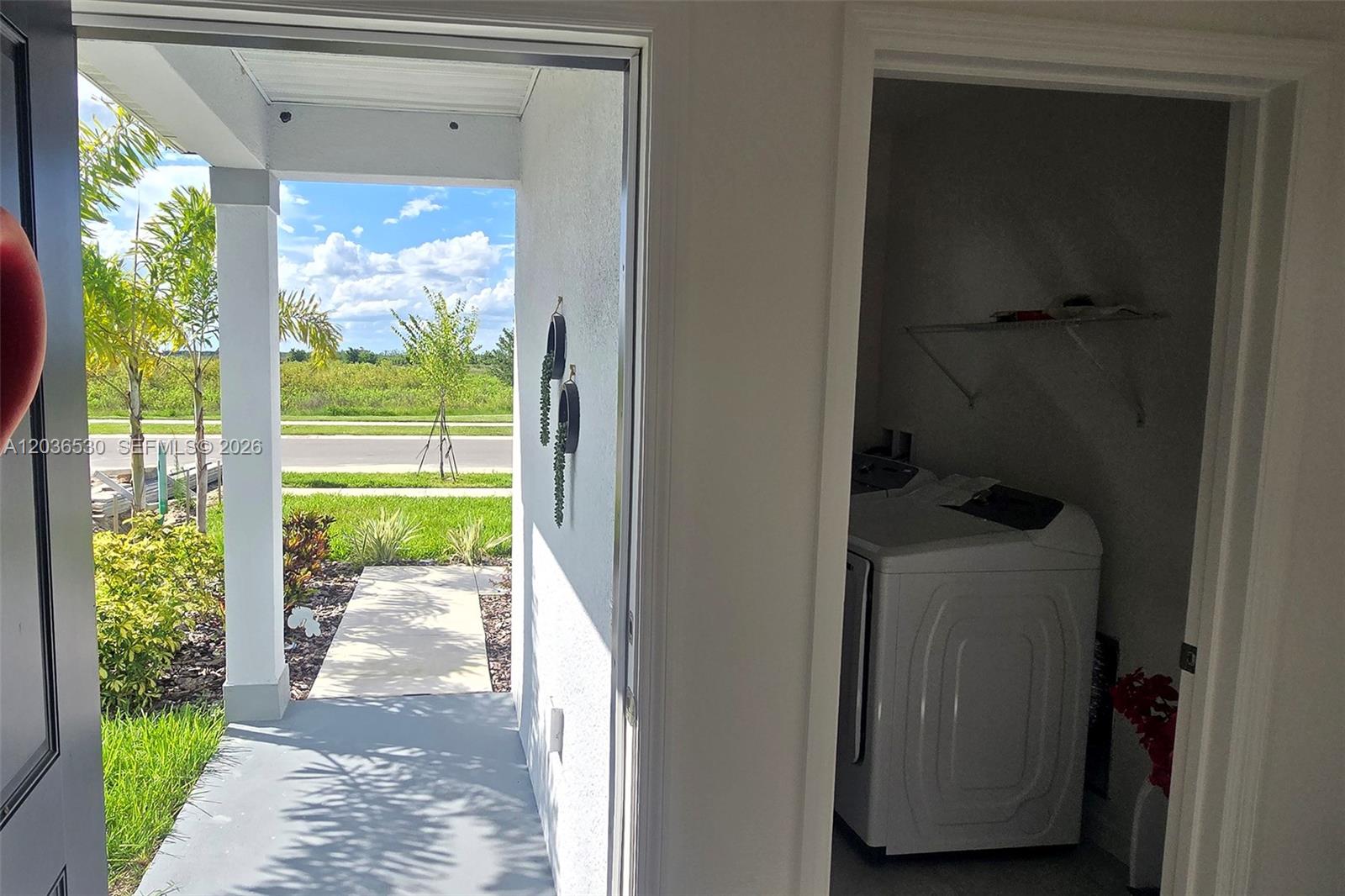 A view from a doorway shows a laundry closet and an outdoor covered entryway — 5539 MADDIE DR, Davenport FL 33844, DAVENPORT, FL