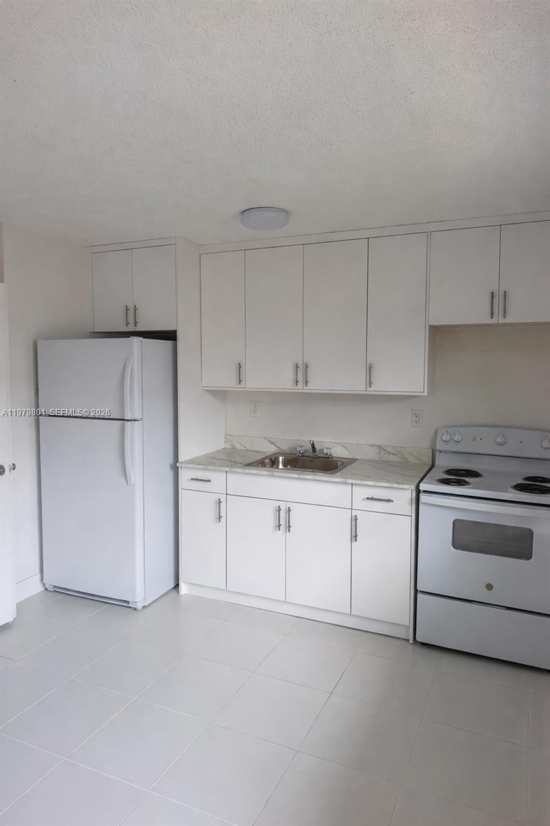 A kitchen features white cabinets, a white refrigerator, a white stove, and a stainless steel sink — 1077 NW 45th Ave # 0, Miami FL 33126, MIAMI, FL