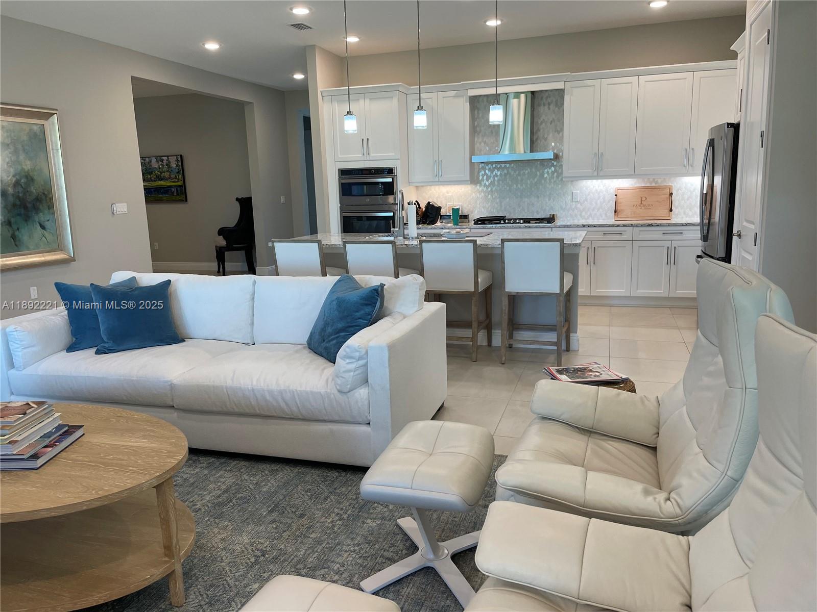A bright open-concept kitchen and living area featuring white cabinetry and modern furniture — 4960 Surfside Circle, Bradenton FL 34211, BRADENTON, FL