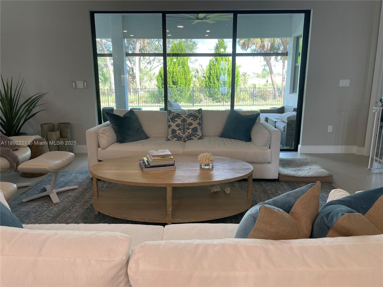 A living room features a white sofa, oval wooden coffee table, and large glass sliding doors — 4960 Surfside Circle, Bradenton FL 34211, BRADENTON, FL