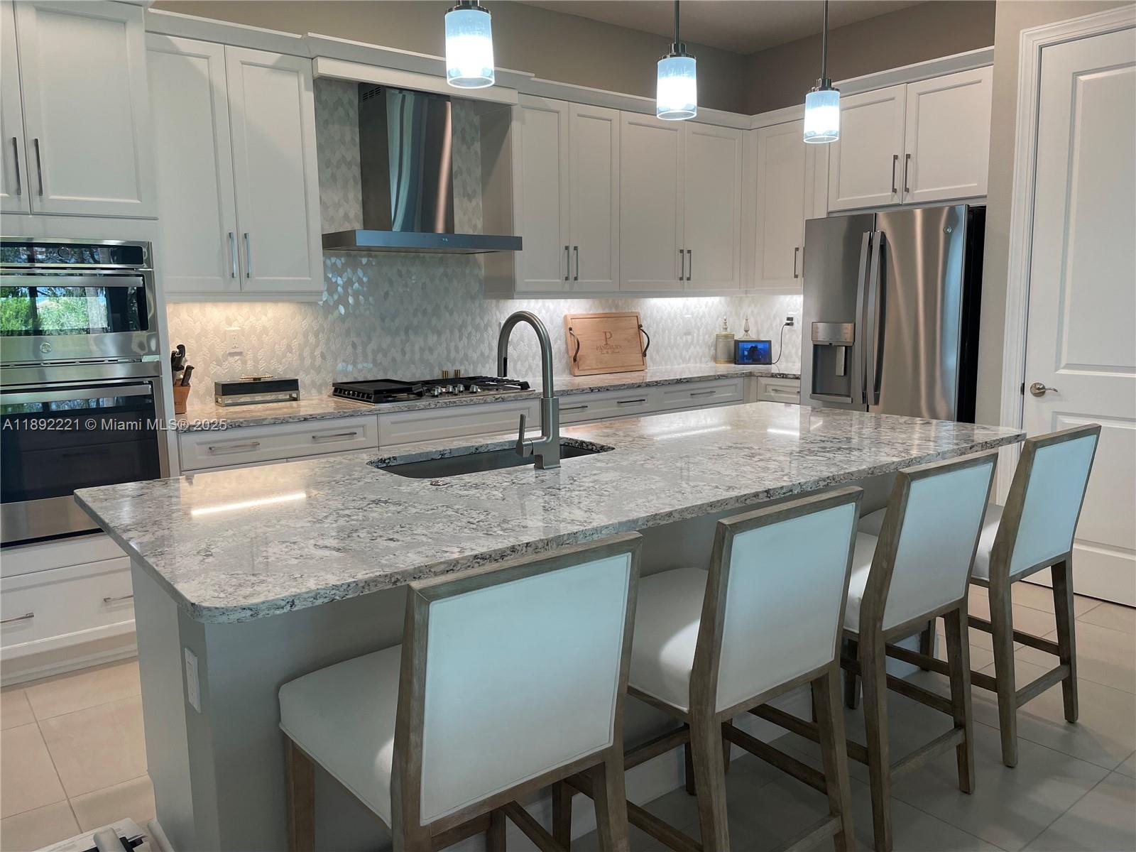 A modern kitchen features white cabinetry, granite countertops, a large island, and stainless steel appliances — 4960 Surfside Circle, Bradenton FL 34211, BRADENTON, FL
