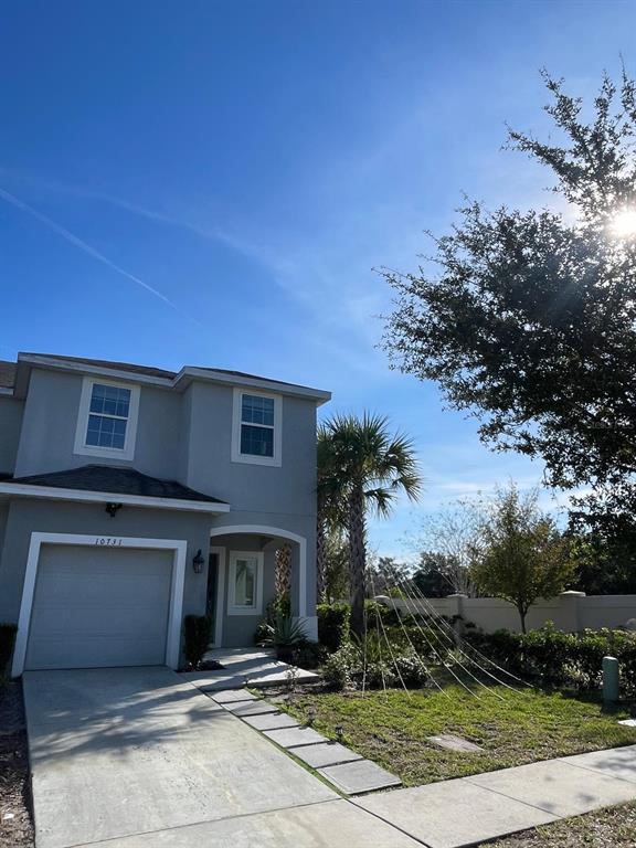 A two-story gray house with a garage, a concrete driveway, and a small front yard — 10731 SILK TREE COURT, ORLANDO, FL