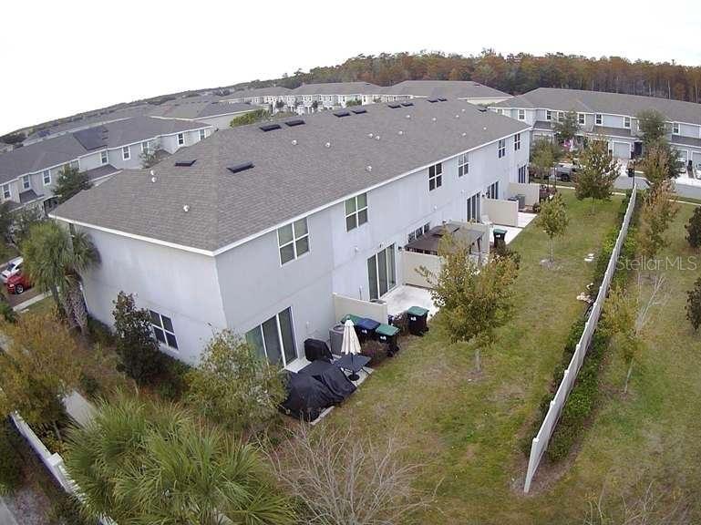 An aerial view shows the rear exterior of a multi-unit townhouse with a fenced yard — 10731 SILK TREE COURT, ORLANDO, FL