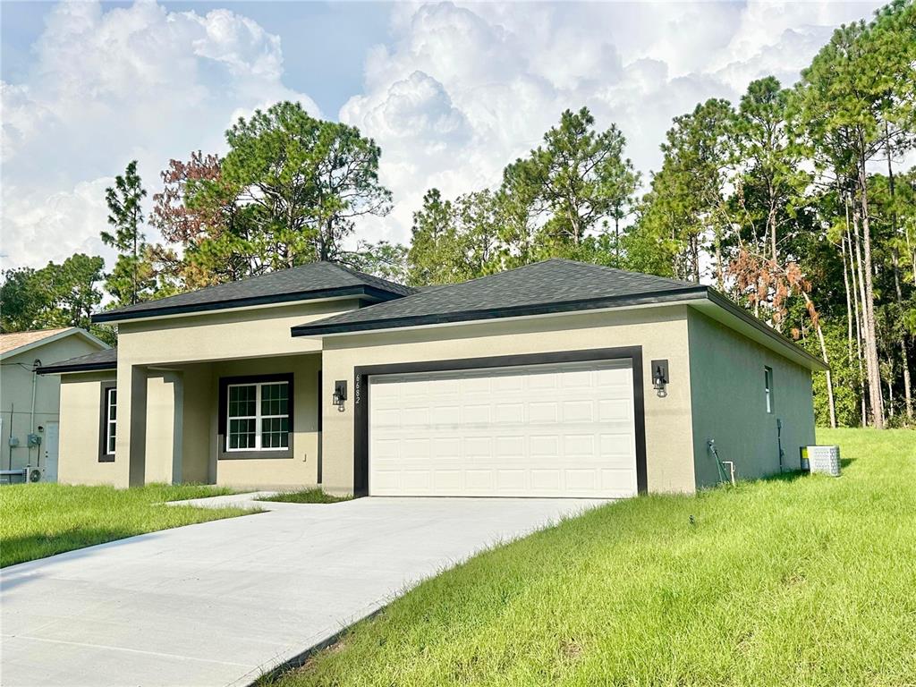 A single-story house with a white garage door, tan stucco exterior, and a concrete driveway — 6682 N EDELWEISS WAY, CITRUS SPRINGS, FL