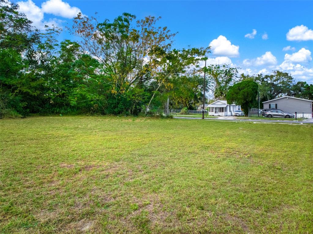 A vacant, grassy residential lot with mature trees and neighboring houses in the background — 0 W STATE ROAD 60, LAKE WALES, FL
