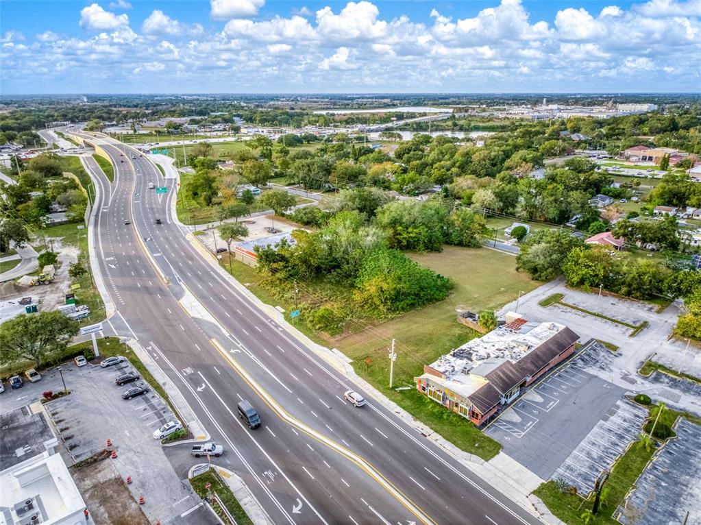 An aerial view shows a multi-lane highway running alongside a commercial building and vacant land — 0 W STATE ROAD 60, LAKE WALES, FL