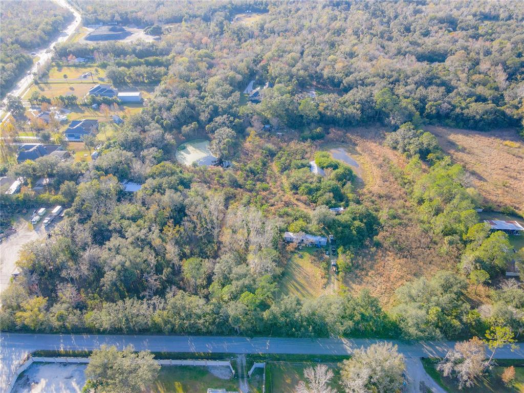 An aerial view shows a wooded property with two small ponds and a single-story house — 1050 VAN ARSDALE STREET, OVIEDO, FL